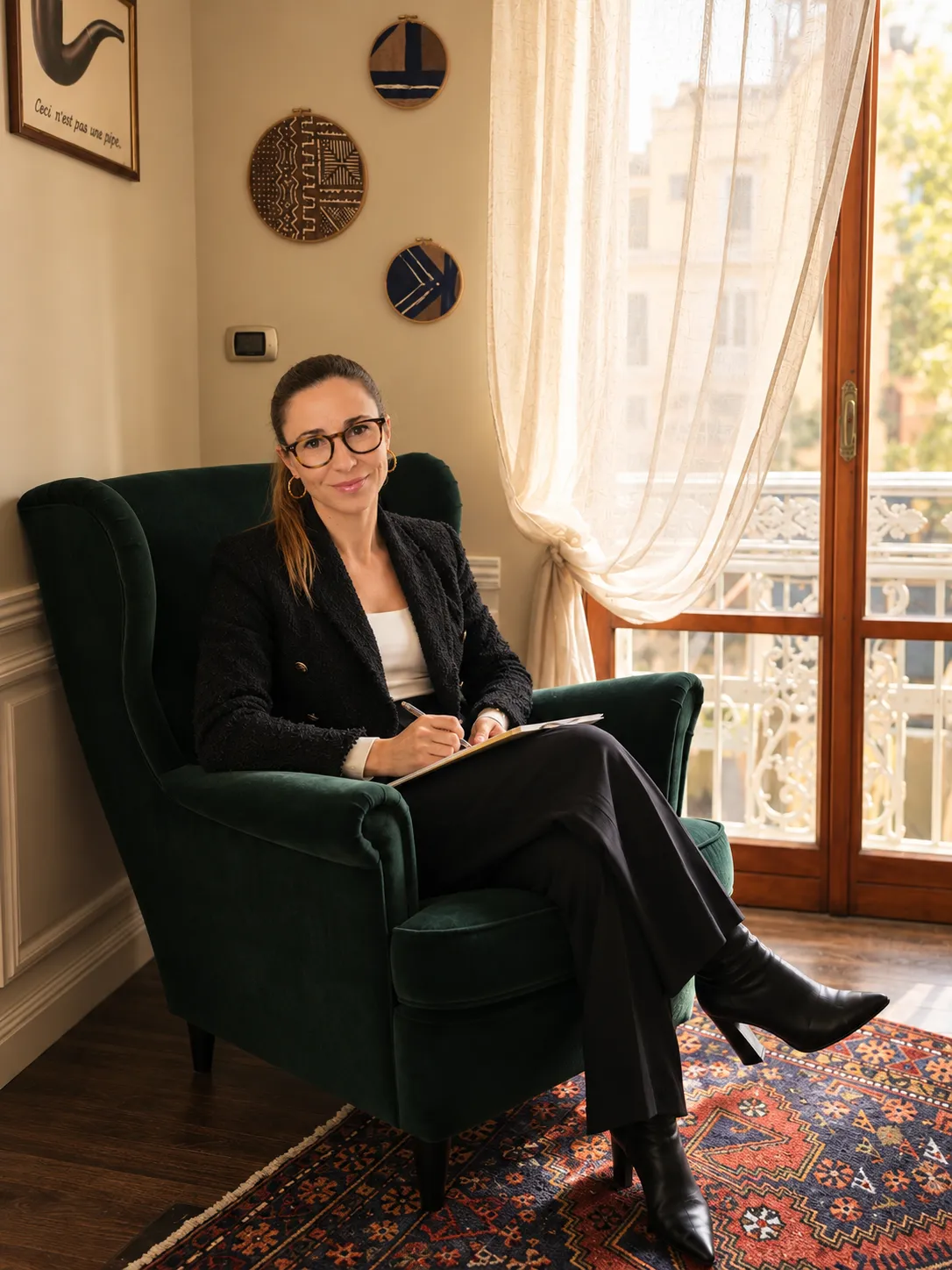 La Dott.ssa Laura Castaldo, psicologa e psicoterapeuta, seduta sulla poltrona verde del suo studio a Napoli mentre prende appunti accanto alla finestra.