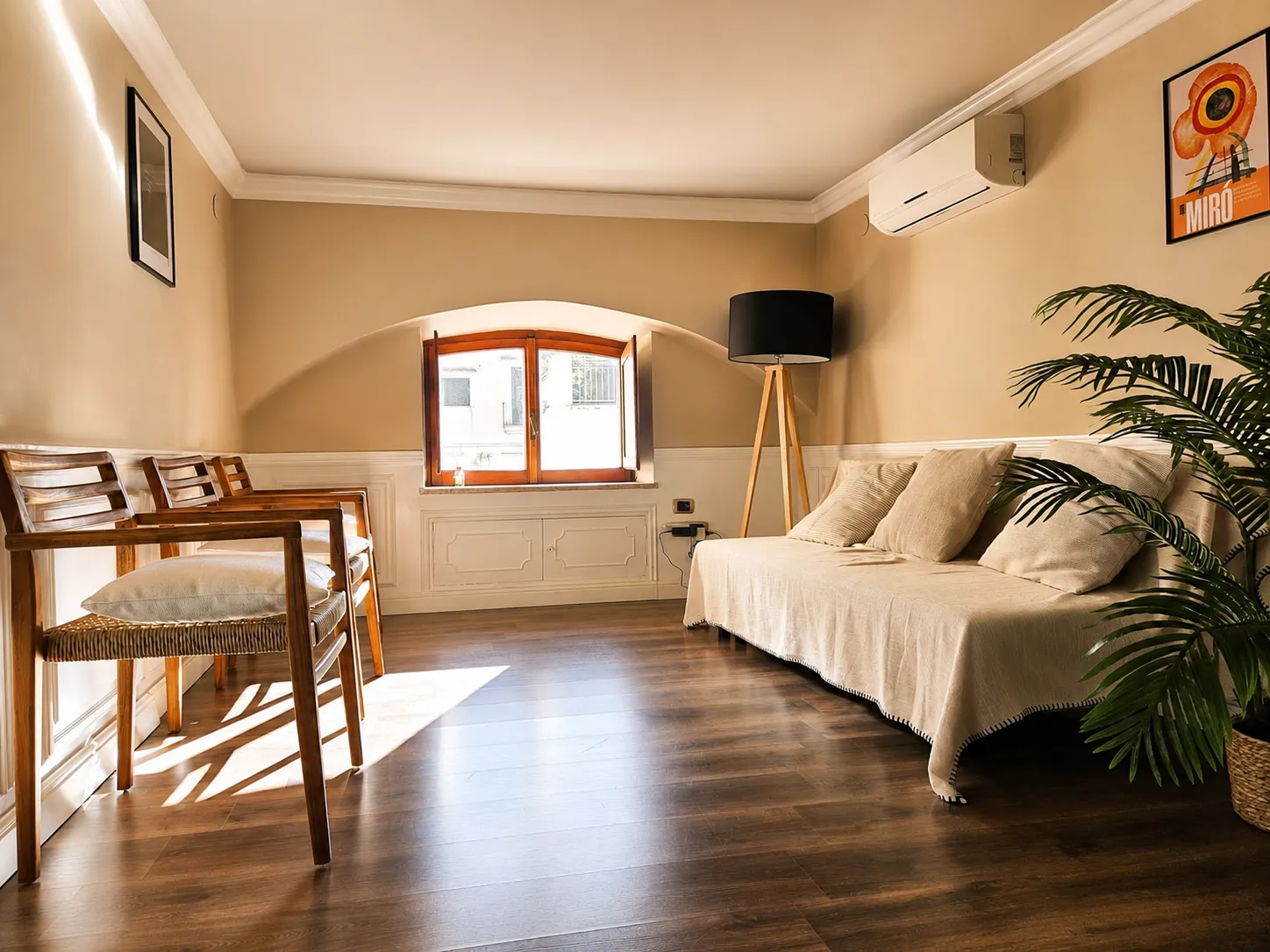 Sala d'attesa dello studio a Napoli, con divano chiaro, sedie in legno, finestra ad arco e pianta.
